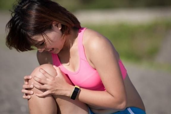 woman with injured knee from sports in need of chiropractic care from arrowhead clinic.